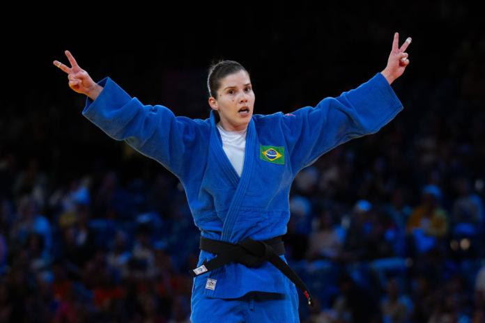 A female Para judo athlete wearing a blue judogi is celebrating